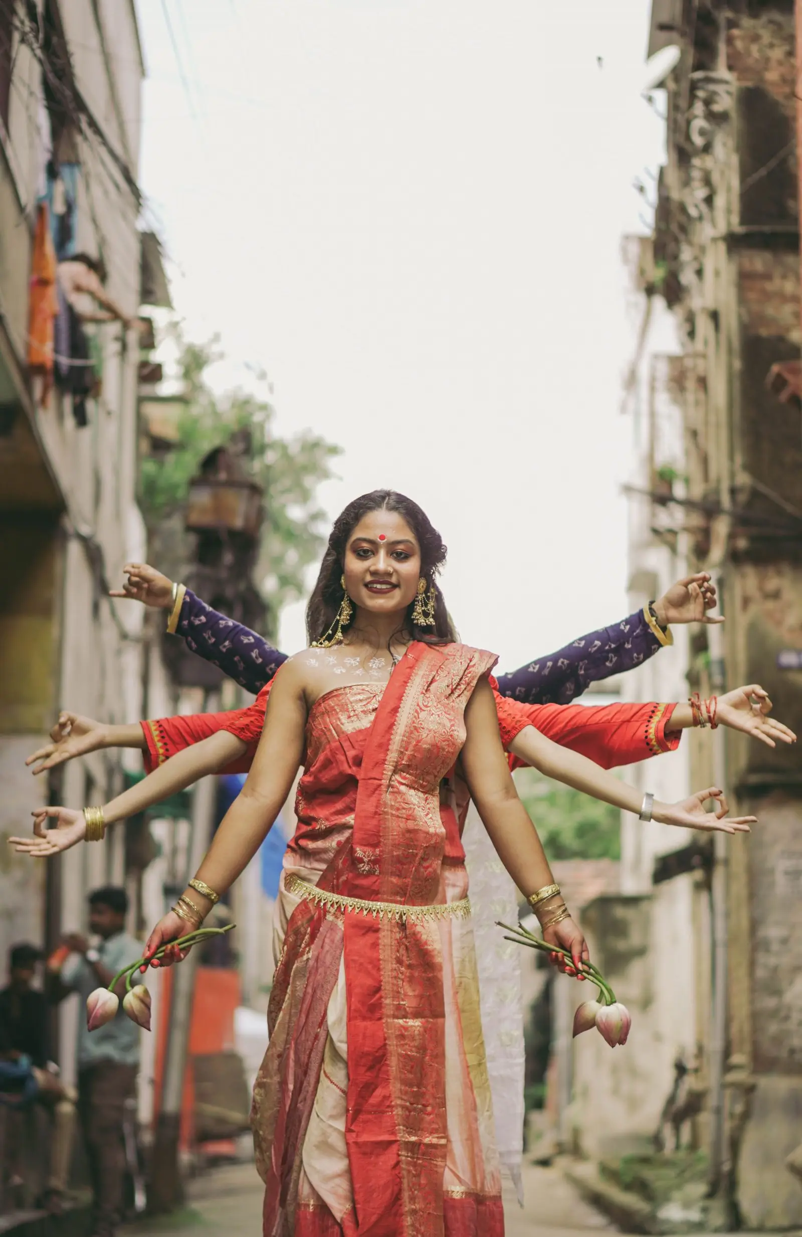 A Bengali woman in a red-and-gold saree, with other women forming Maa Durga's ten hands around her, Kolkata